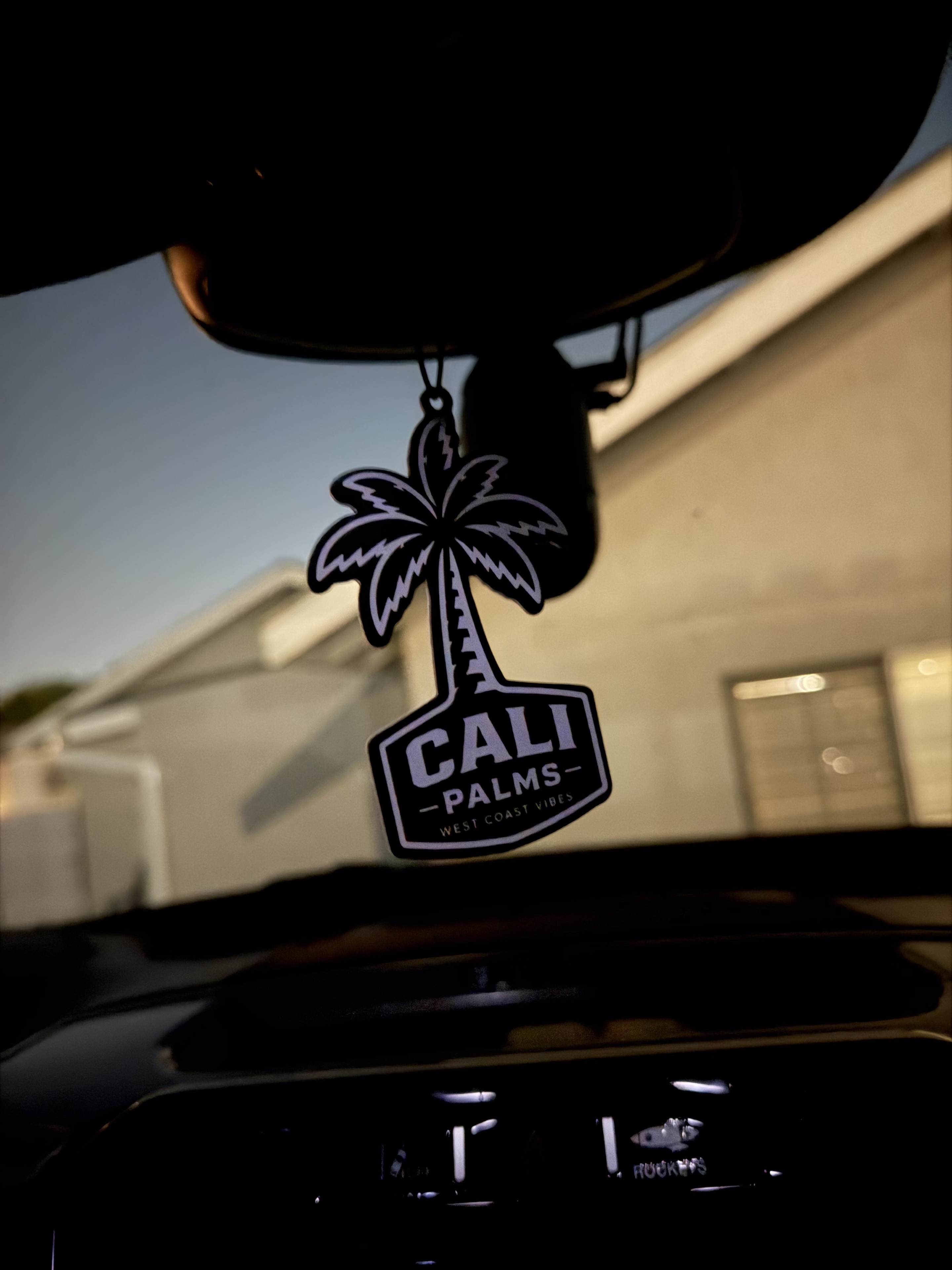 CALI PALMS palm air freshener hanging from a rearview mirror