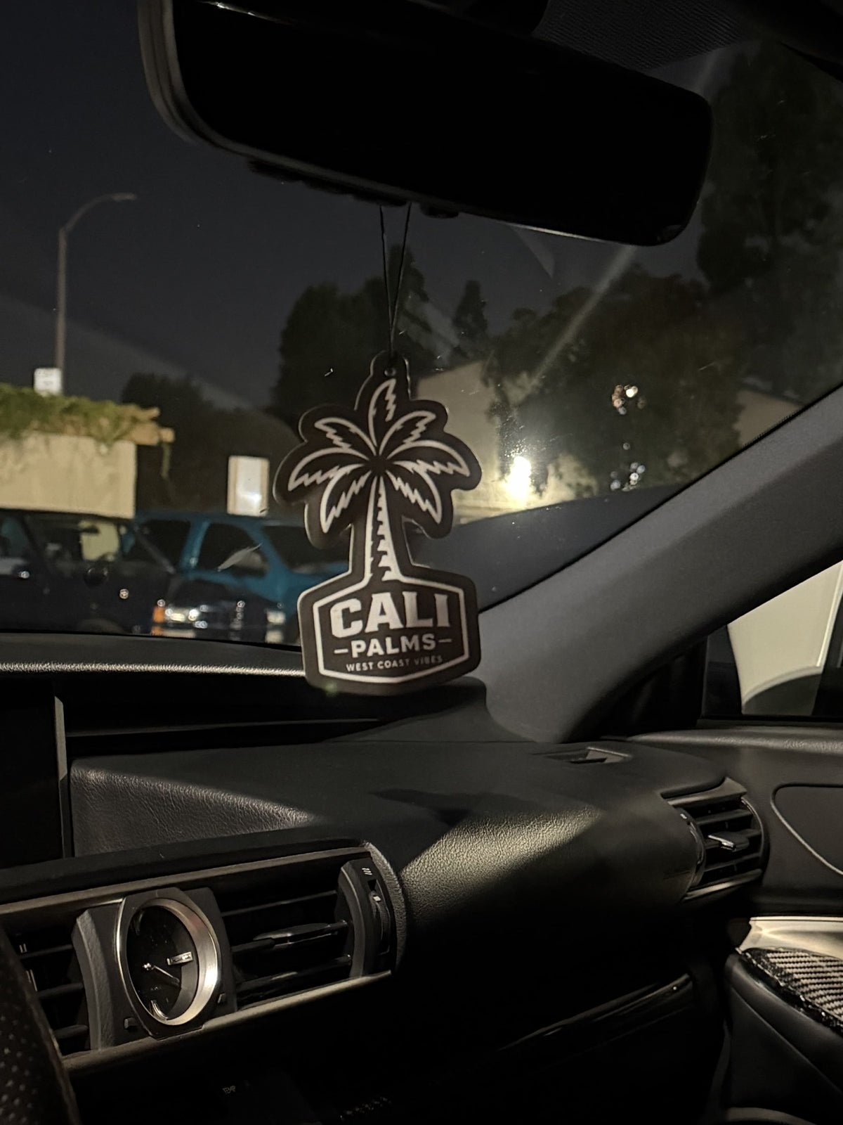 Black Cali Palms air freshener hanging above a modern car dashboard